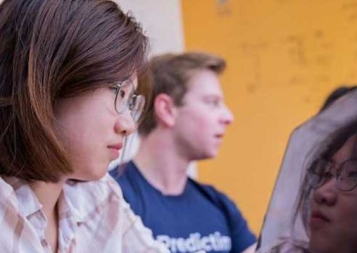 Close up photo of Iris Yuning working on laptop with mirror image of herself showing