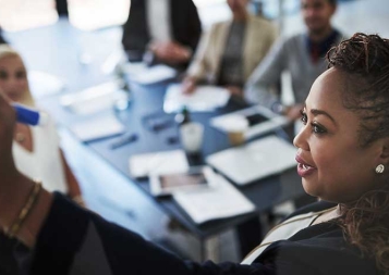 Black woman professional leading meeting while drawing on a white board