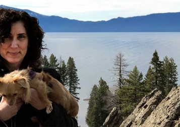 Marianna Lenoci posing in front of a Sierra lake while holding her puppy