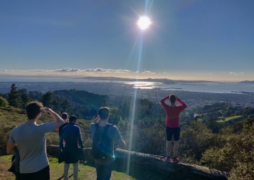 BHGAP student Markus and a few friends looking at a beautiful view of mountains and the ocean during a hike