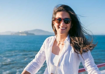 Photo of Perline Hochart wearing all white clothes while on a sailboat on the San Francisco Bay