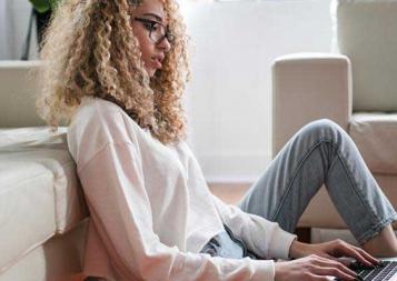 Black woman sitting on the floor typing on a laptop