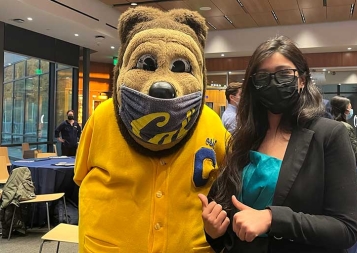 Shreya Nemani and Oski bear post for the camera inside the Haas building