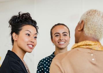 Colleagues in an office setting, standing and discussing ideas with interest