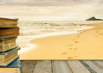 Stack of books on a wood platform on a beach