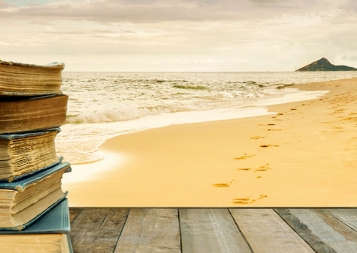 stock photo of a stack of books on a woden table by the beach