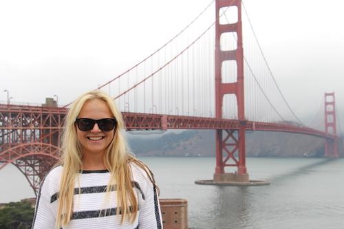 German student Anna Julia poses with sunglasses in front of the Golden Gate bridge