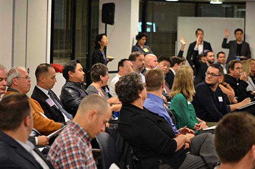 Audience members raising their hand to ask questions of the panelists