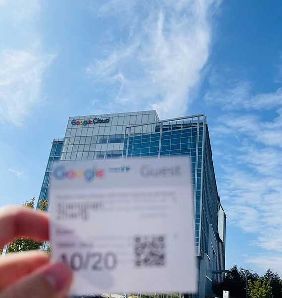 Xiangjian Zhang holding up pass in front of Google building