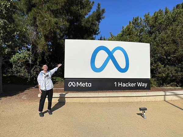 Xiangjian Zhang standing in front of Meta sign