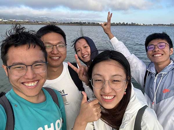 Xiangjian Zhang and friends standing in front of the beach